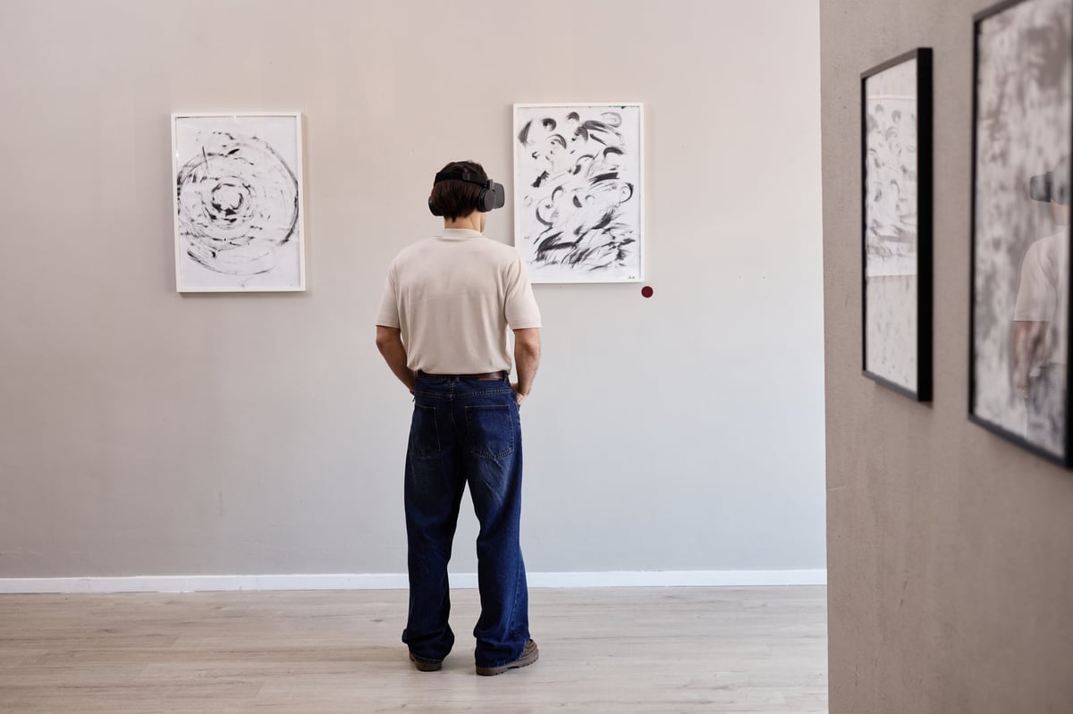 Young adult man wearing virtual reality headset observing abstract art on gallery wall